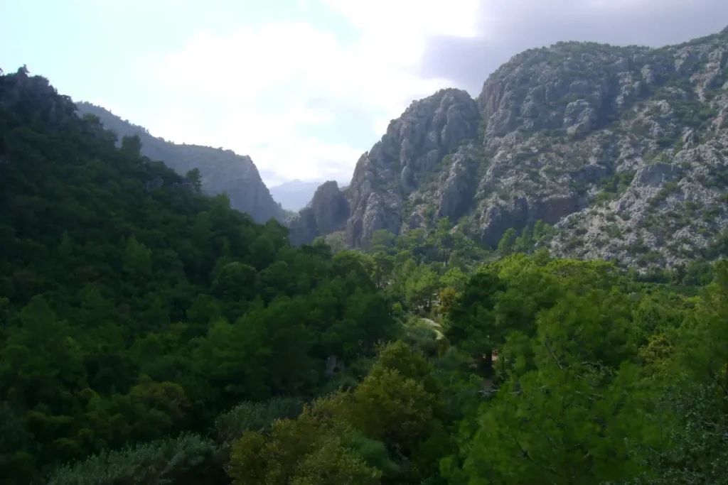 This photo captures the valley where the ancient city of Olympos was built, surrounded by towering rocky mountains and lush forests.