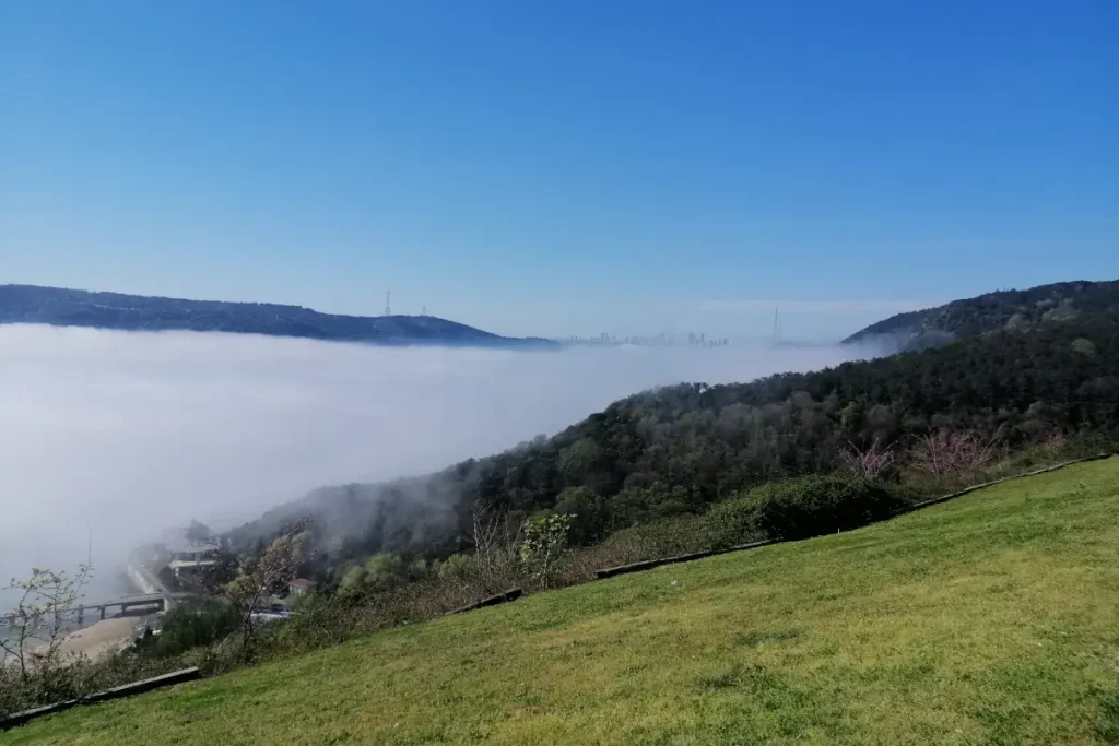 The Bosphorus is under heavy fog. The Maslak skyscrapers can be seen on the horizon.