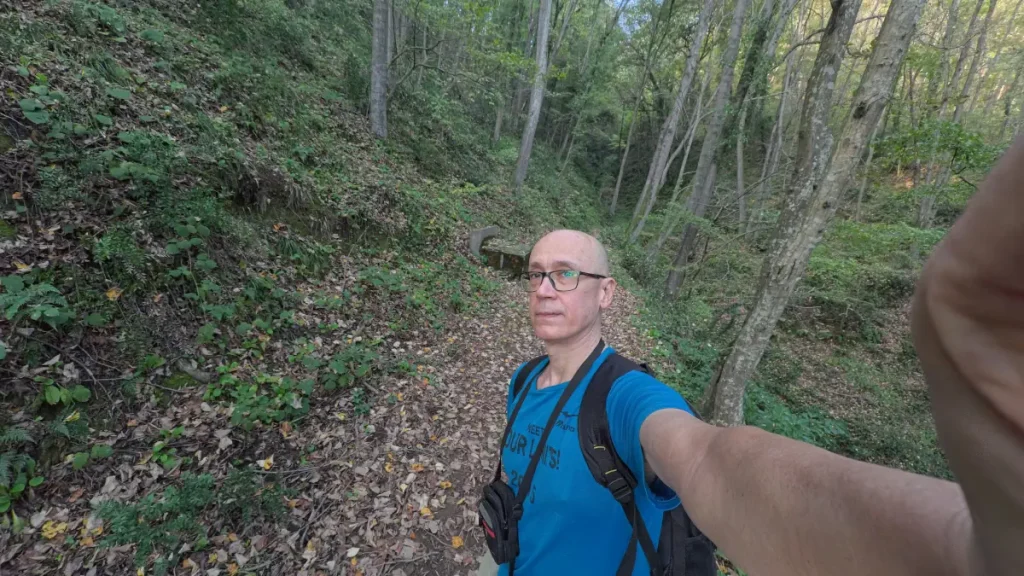 Selfie of Özgür Nevres standing on a leaf-covered trail in the Belgrad Forest during a November afternoon hike, surrounded by tall trees and dense greenery.