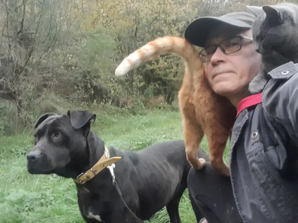 Me at our sanctuary with Zeytin (Olive) standing beside me, one cat resting on my shoulders and another sitting calmly on my lap.
