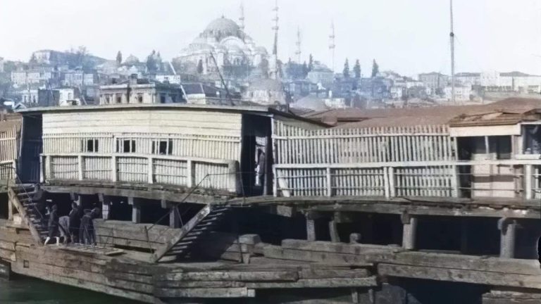 Colorized frame from the oldest video of istanbul [1897] showing the old Galata Bridge over the Golden Horn, with wooden structures, boats on the water, pedestrians on the bridge, and the Historic Peninsula with domes and minarets in the background