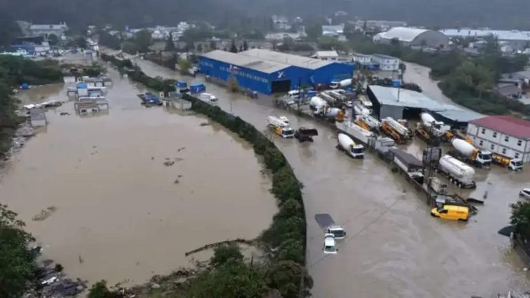 Aerial view of severe flooding in Istanbul during October 2026, showing muddy floodwaters covering an industrial area, partially submerging vehicles, and surrounding warehouses, factories, and roads.